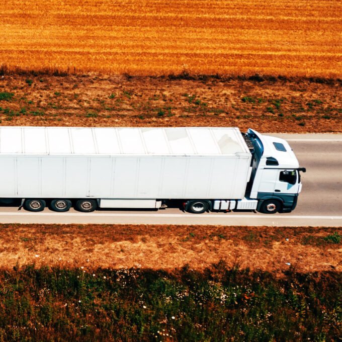 White truck on highway through countryside landscape, aerial sho White truck on highway through countryside landscape, aerial sho